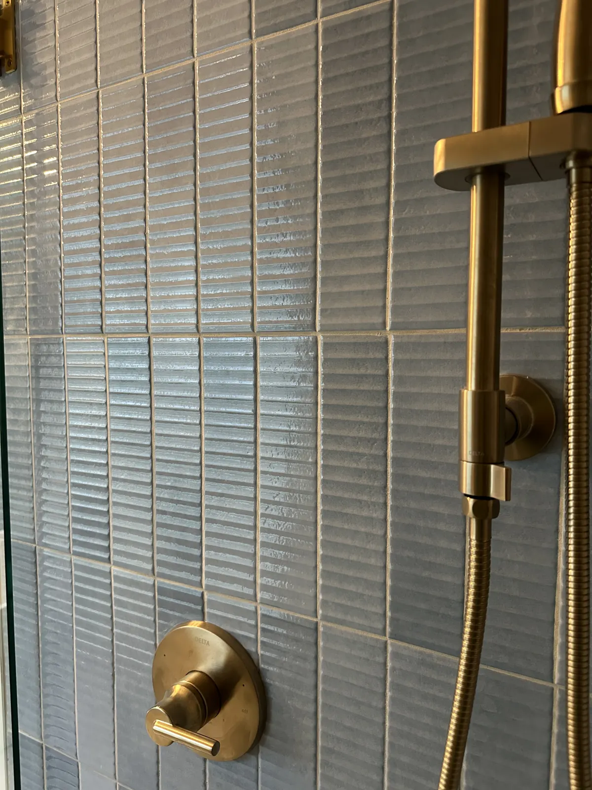 Brushed brass shower valve centered on vertical tile