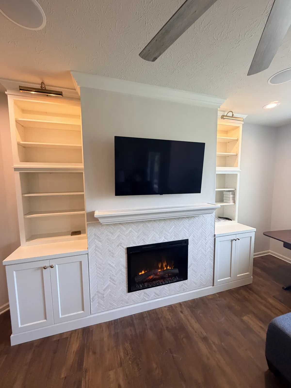 Living room built-ins with lit shelves around a fireplace and TV