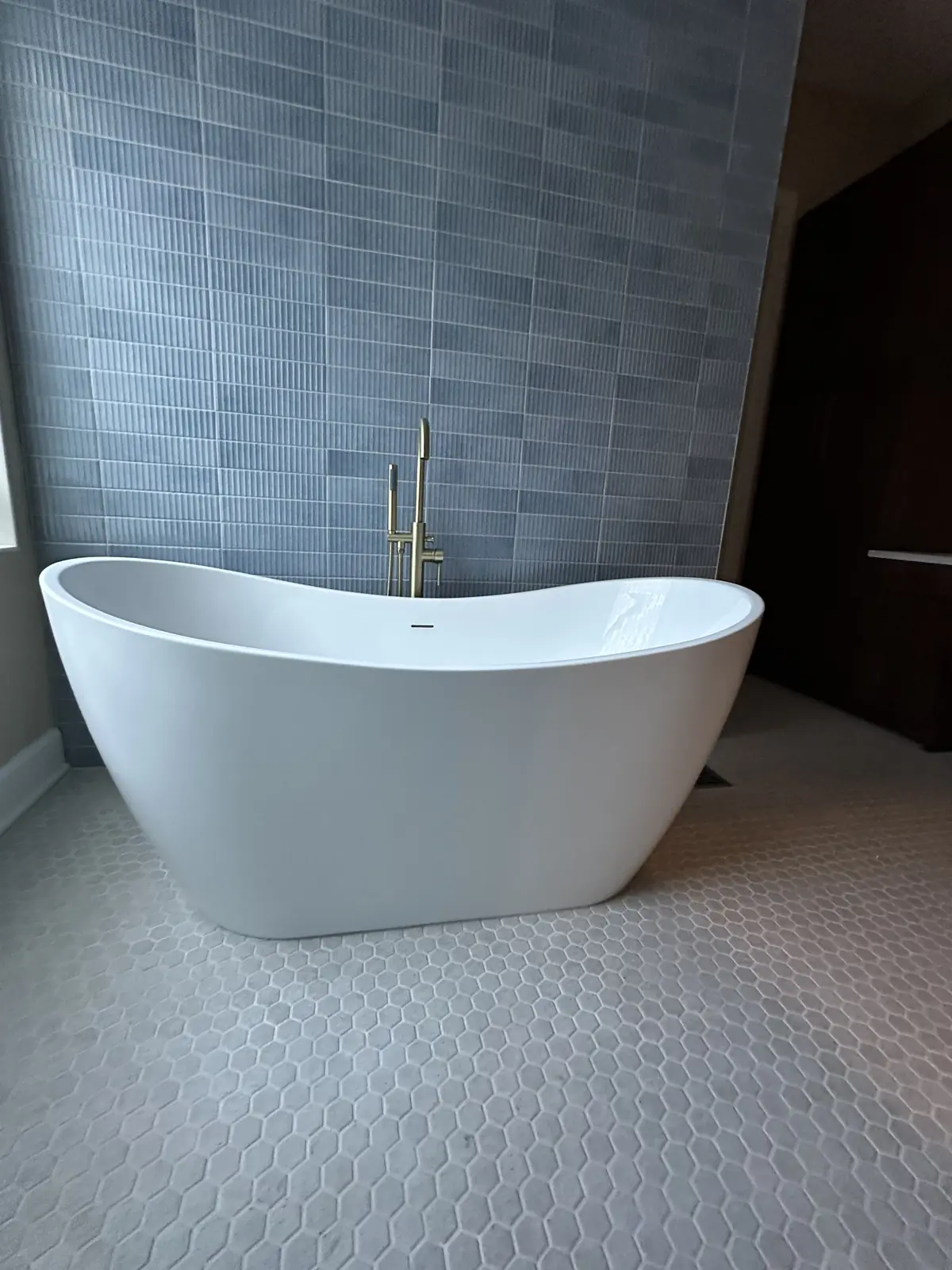 White freestanding soaking tub in front of blue tile