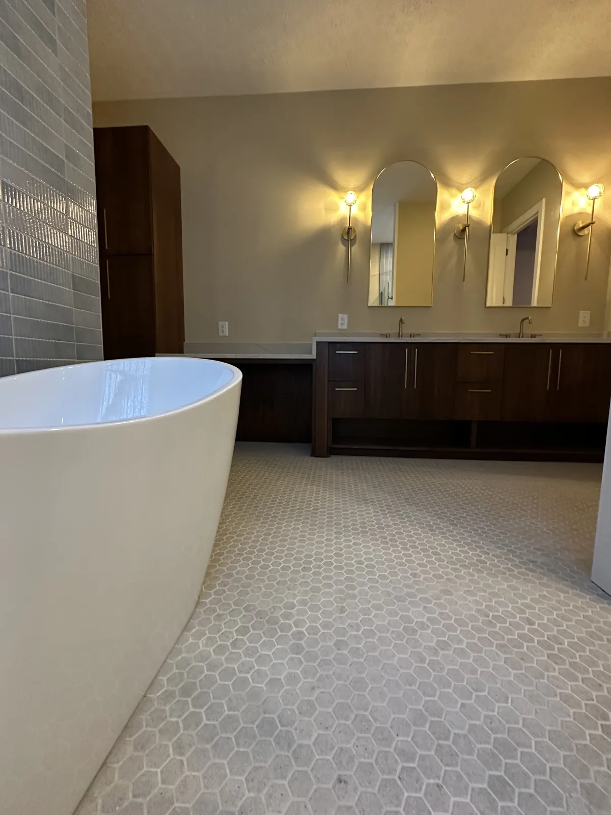Freestanding tub in the foreground with the walnut vanity behind