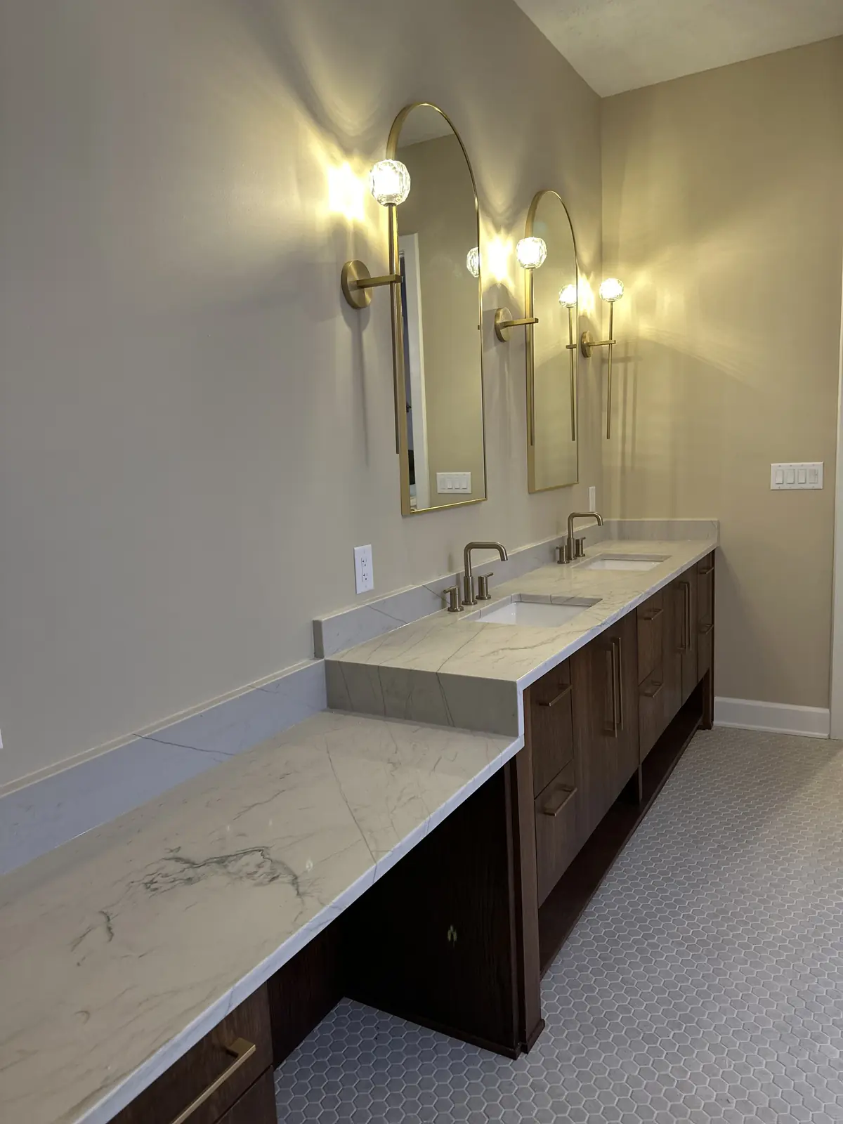 Quartz vanity top and makeup counter lit by brass sconces