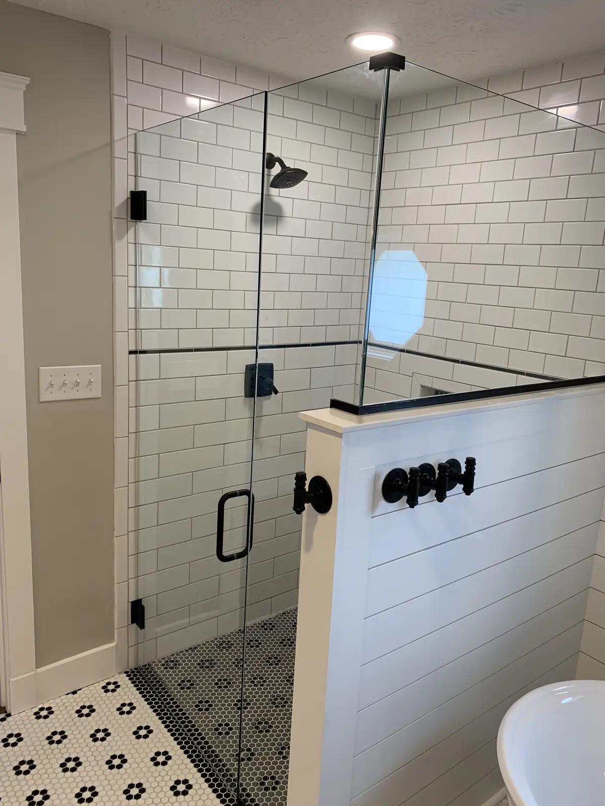 White subway tile shower with a glass panel on a shiplap half wall