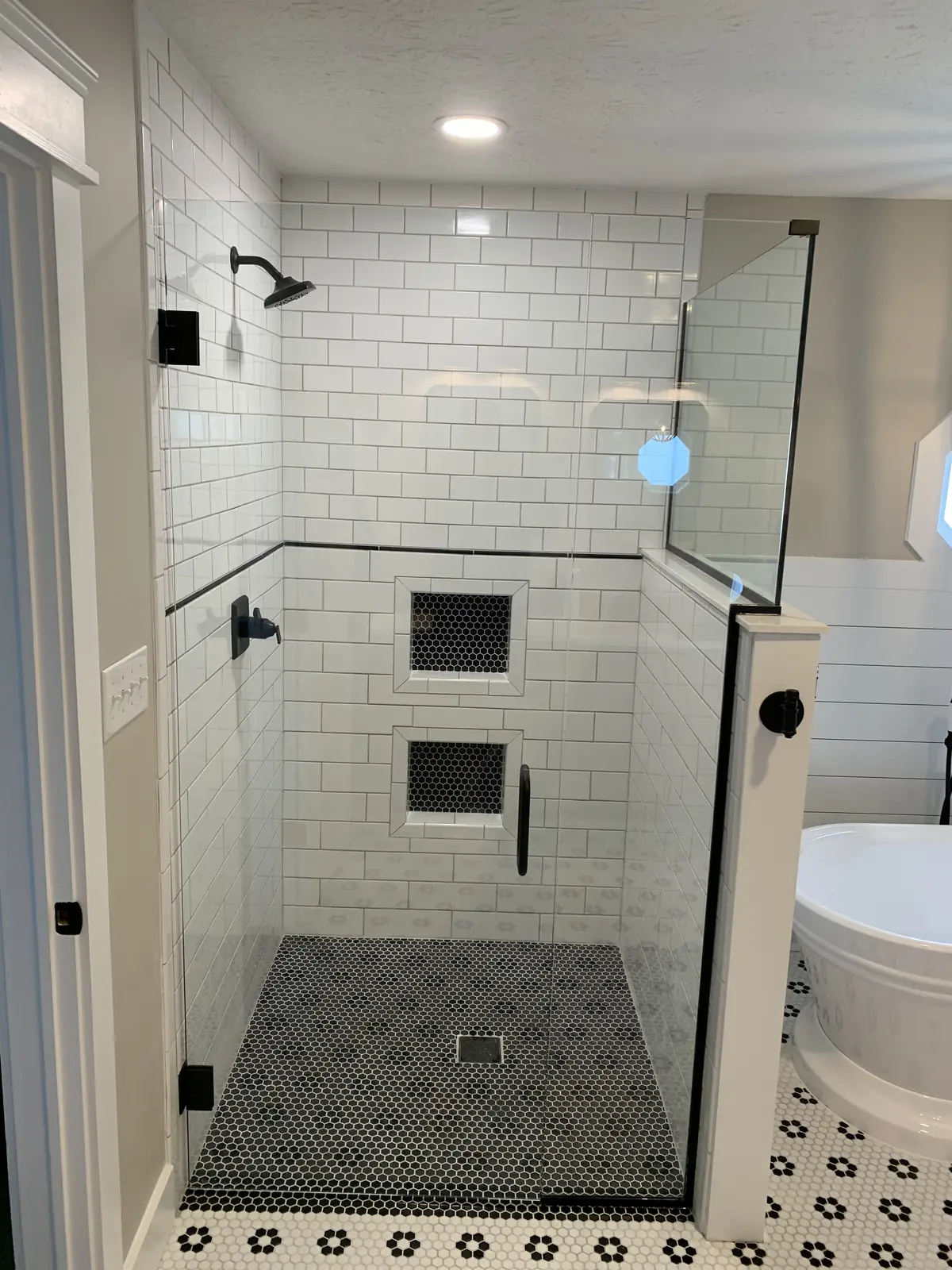 White subway tile shower with two niches and a hex mosaic floor