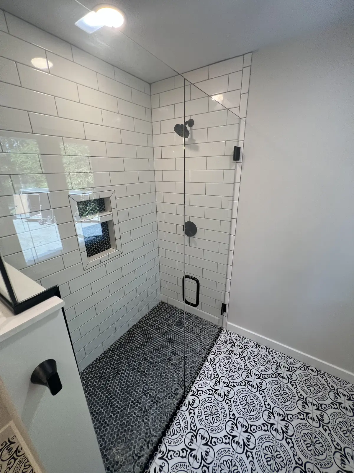 White subway tile shower with frameless glass and a patterned tile floor
