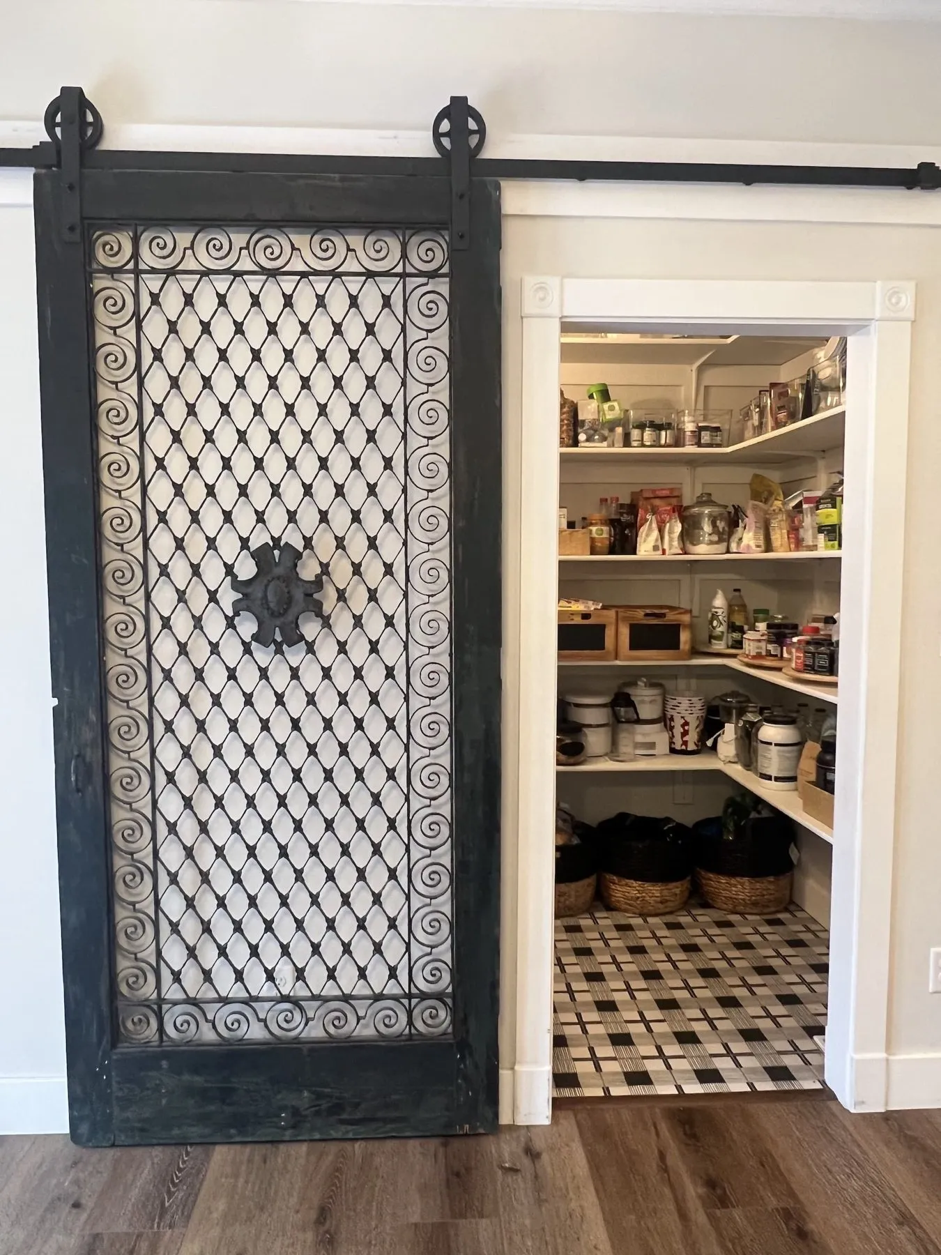 Walk-in pantry behind a black sliding barn door with patterned glass