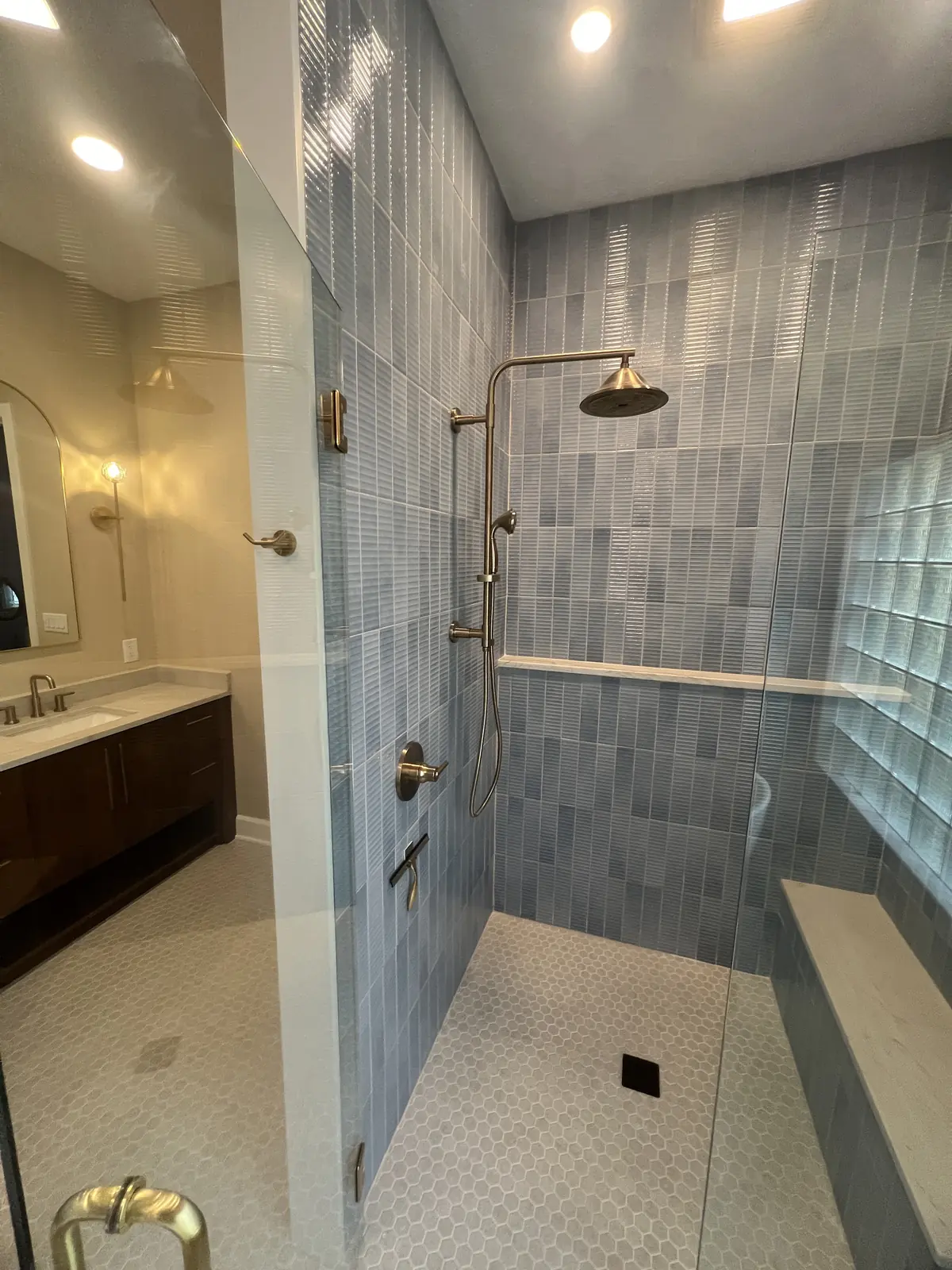 Walk-in shower with a quartz bench, blue tile and glass block window