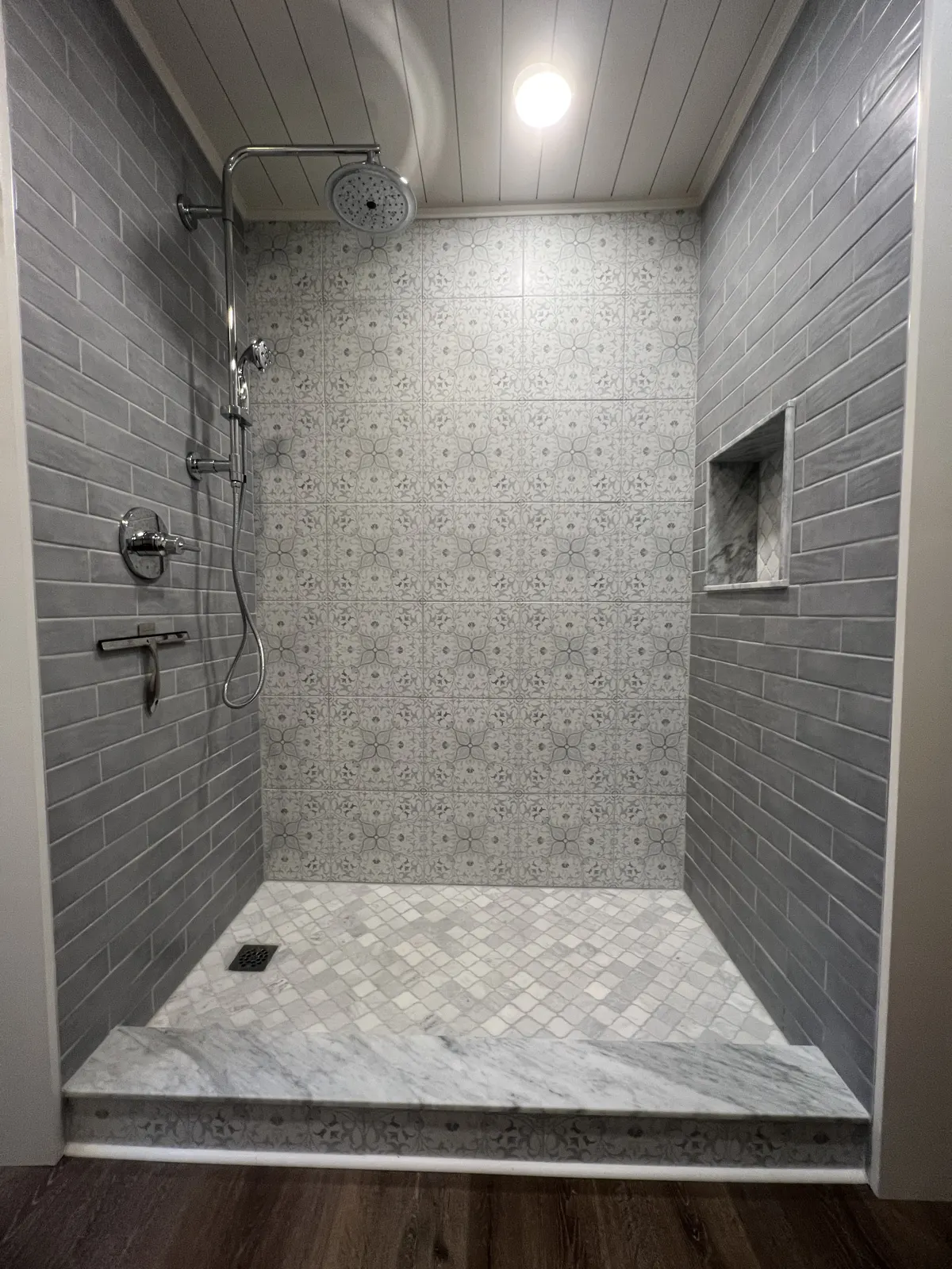 Walk-in tile shower with a recessed niche and mosaic floor