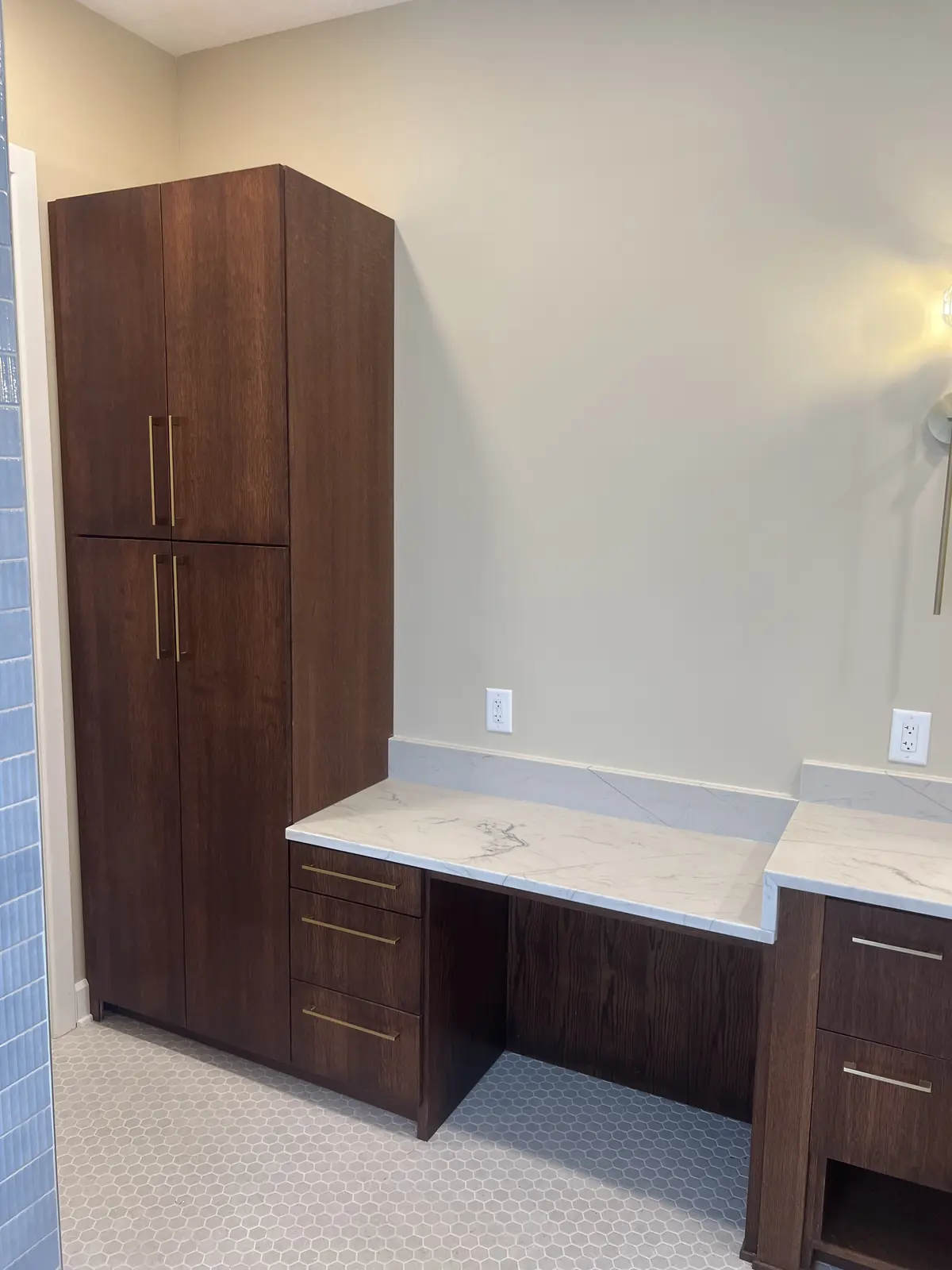 Tall walnut linen tower next to a makeup counter with drawers