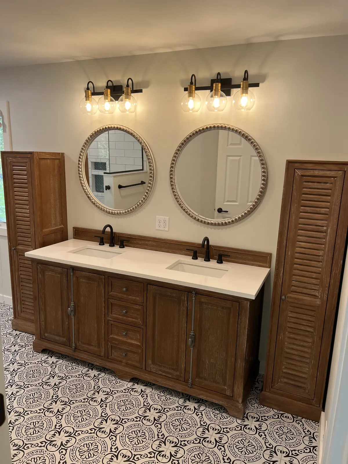 Wood double vanity with round mirrors and patterned floor tile